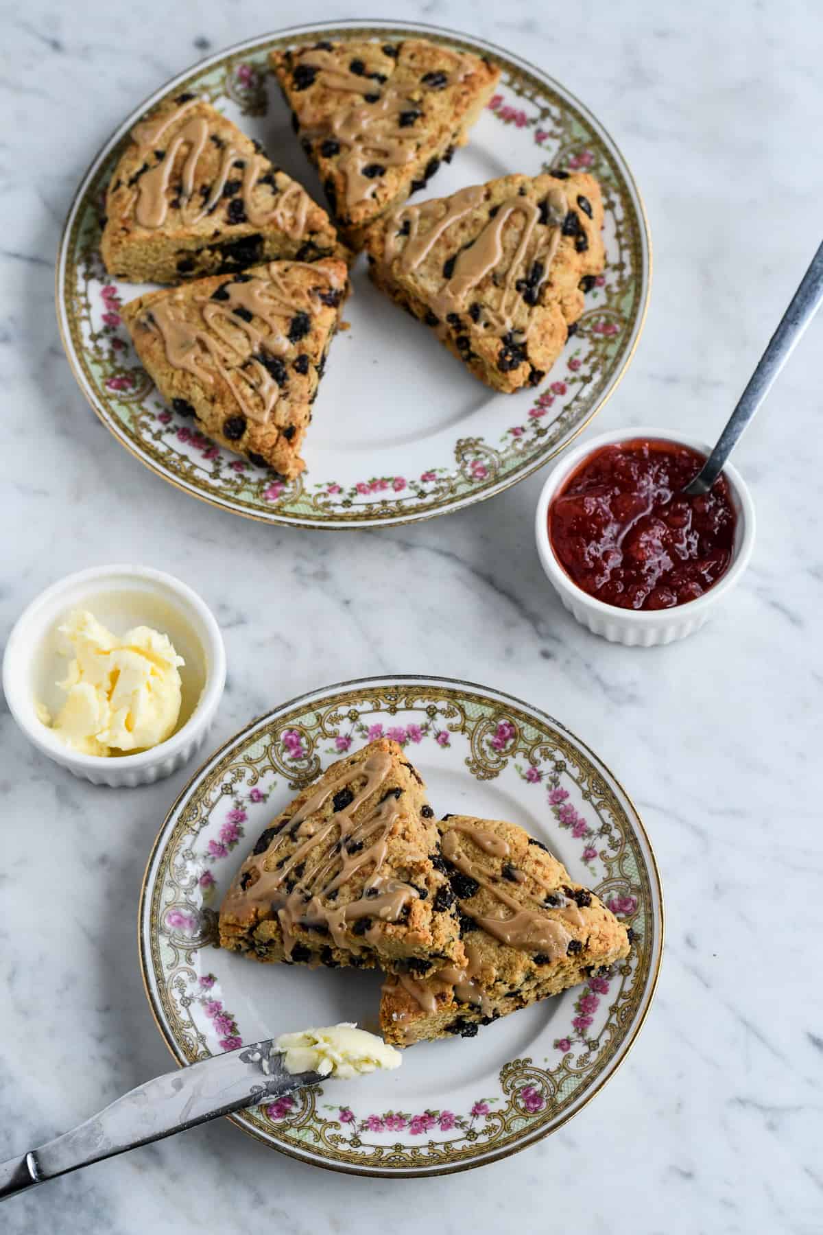 Paleo Currant Scones over with jam, butter and 2 on a separate plae