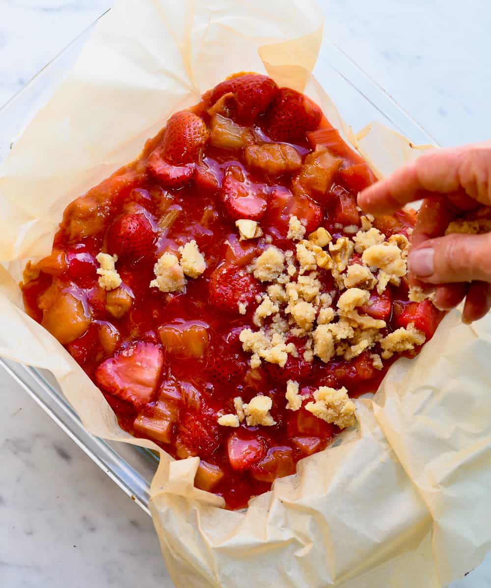 Strawberry Rhubarb Crumb Bars putting on crumb topping