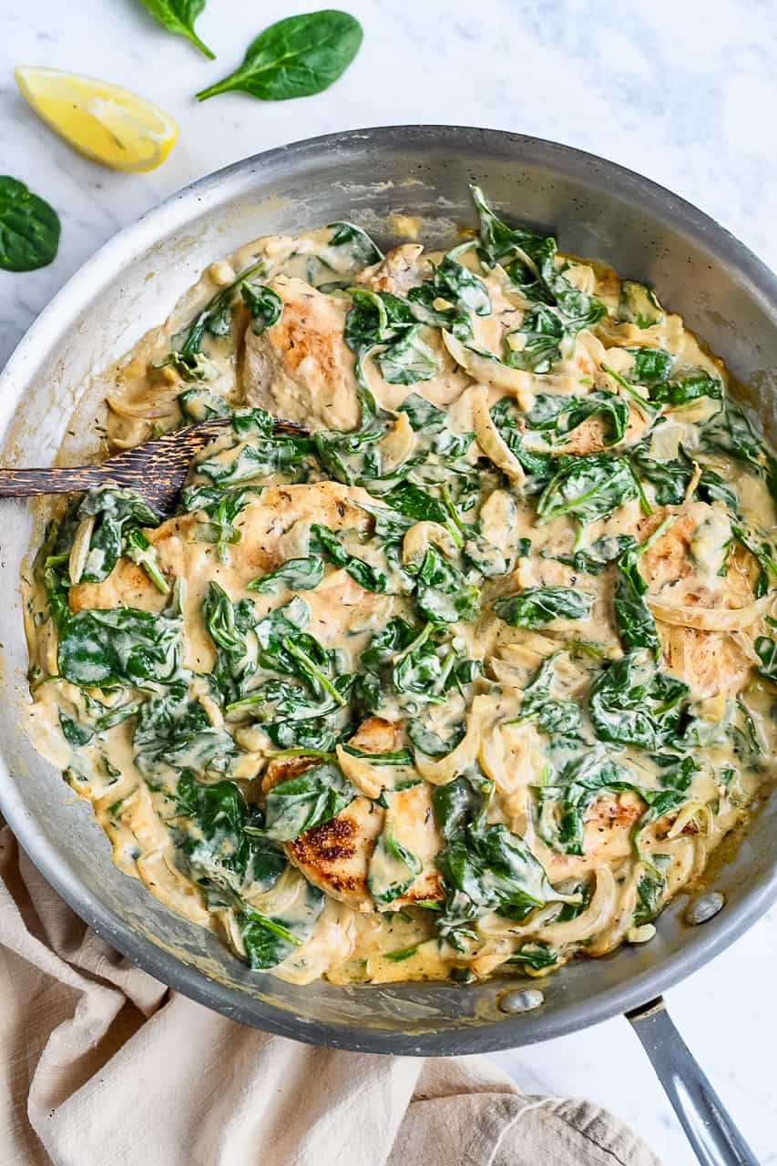 Creamy Spinach Chicken in pan with lemon on side