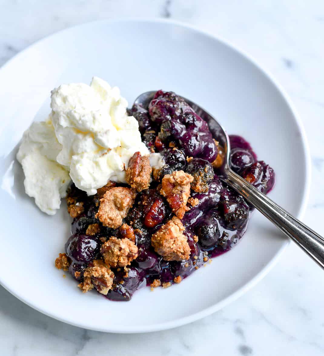 Easy Blueberry Cobbler plate with whipped cream and spoon