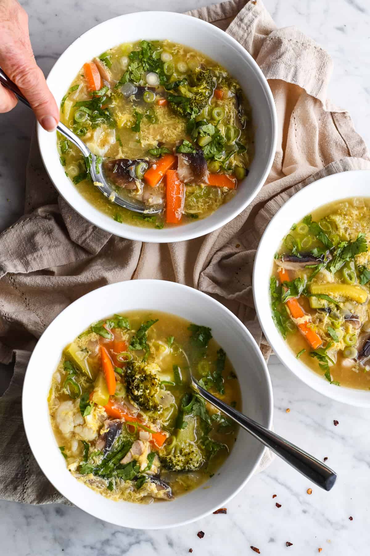 Vegetable Hot and Sour Soup 3 bowls with hand taking soup