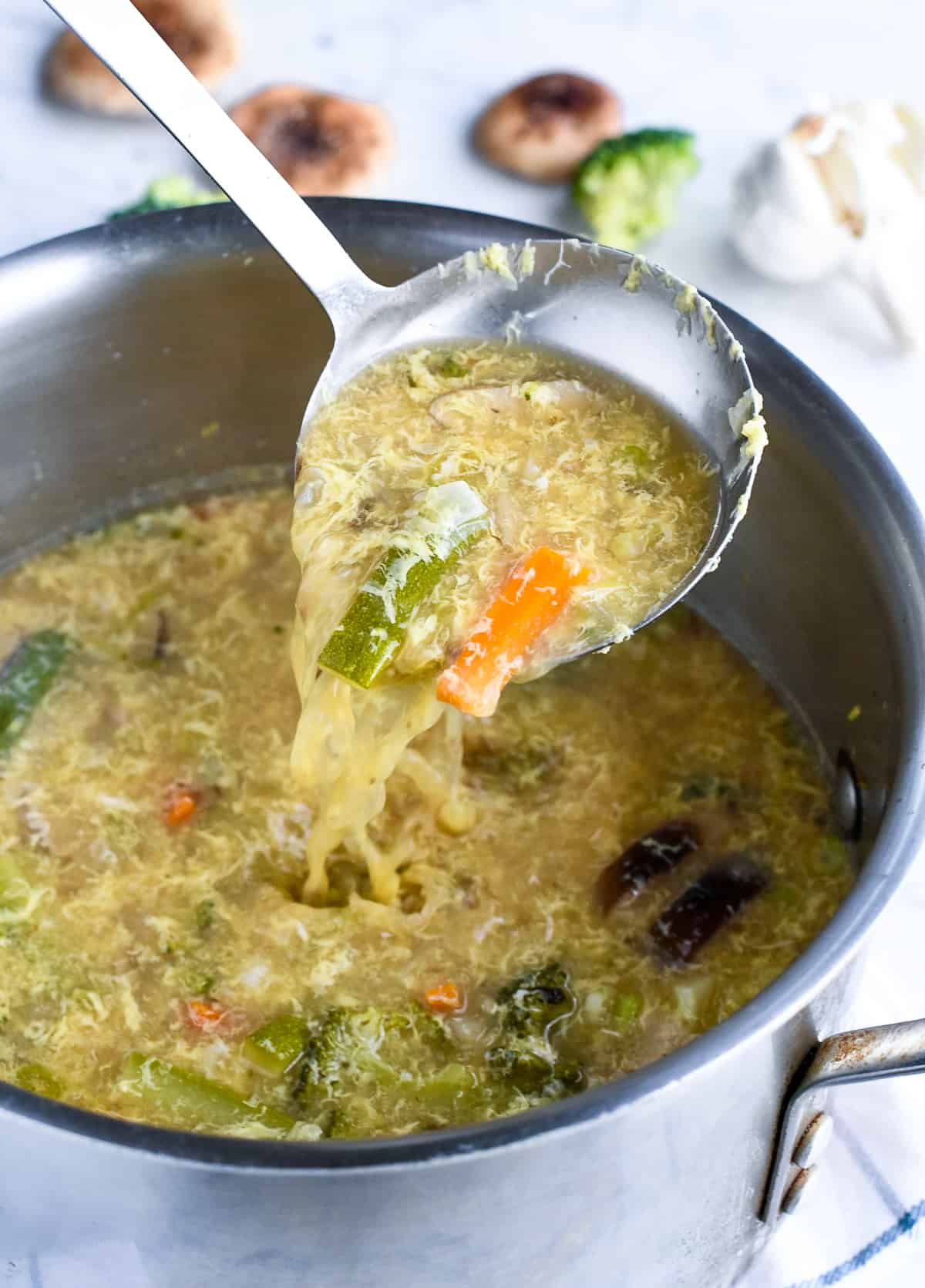 Vegetable Hot and Sour Soup in pot with ladle pouring