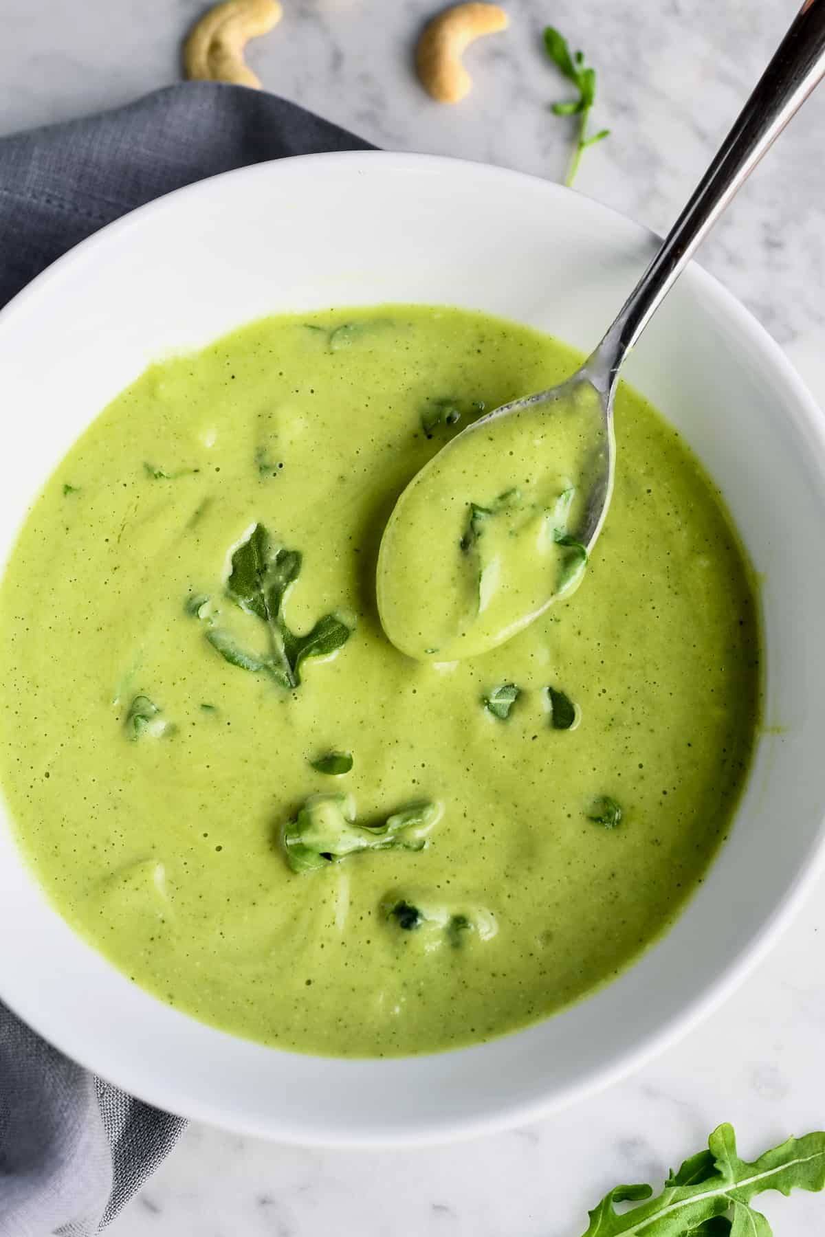 Creamy Zucchini Arugula Soup close up in bowl with spoon