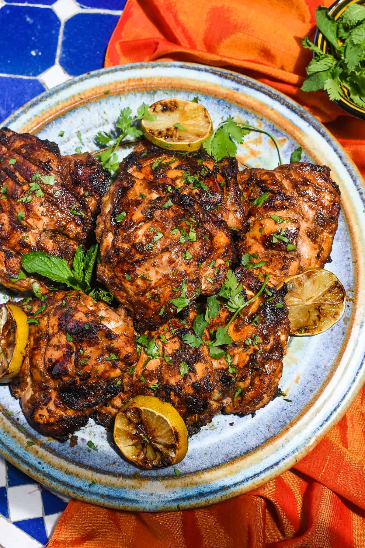 Grilled Tandoori Chicken Thighs on plate with grilled limes