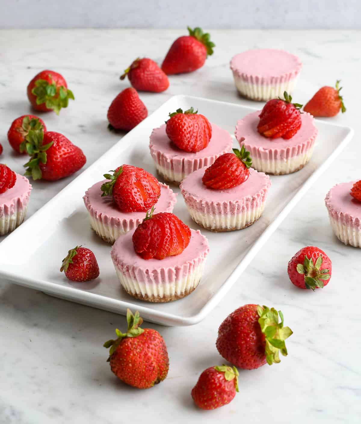 Mini Strawberry Cheesecakes on a platter with fresh strawberries all around