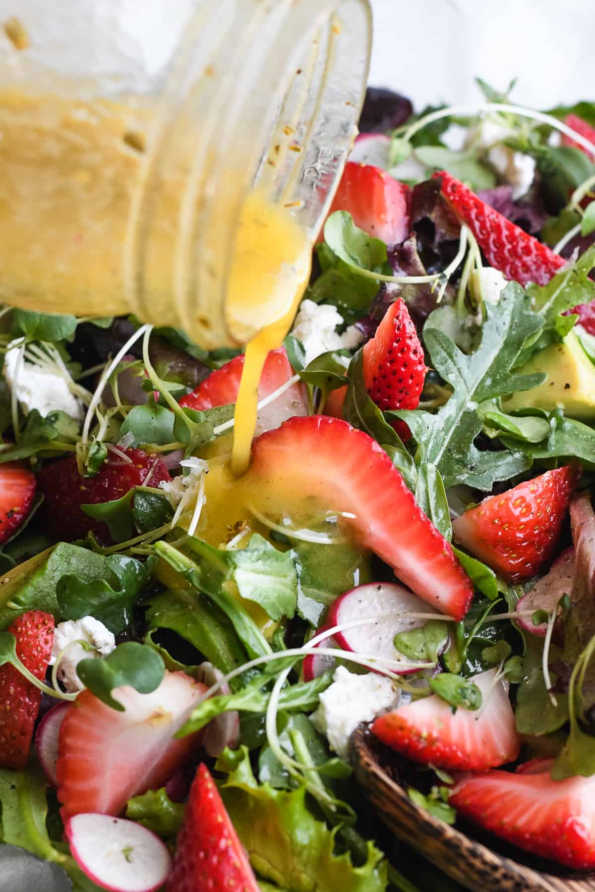 strawberry fields salad close up pouring the dressing