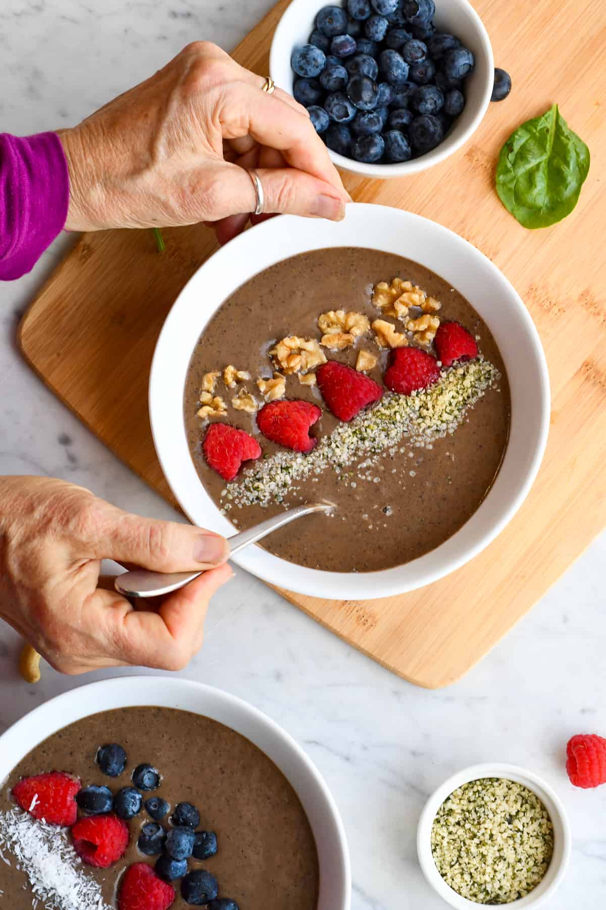 Chocolate Protein Smoothie Bowl with hands on spoon.