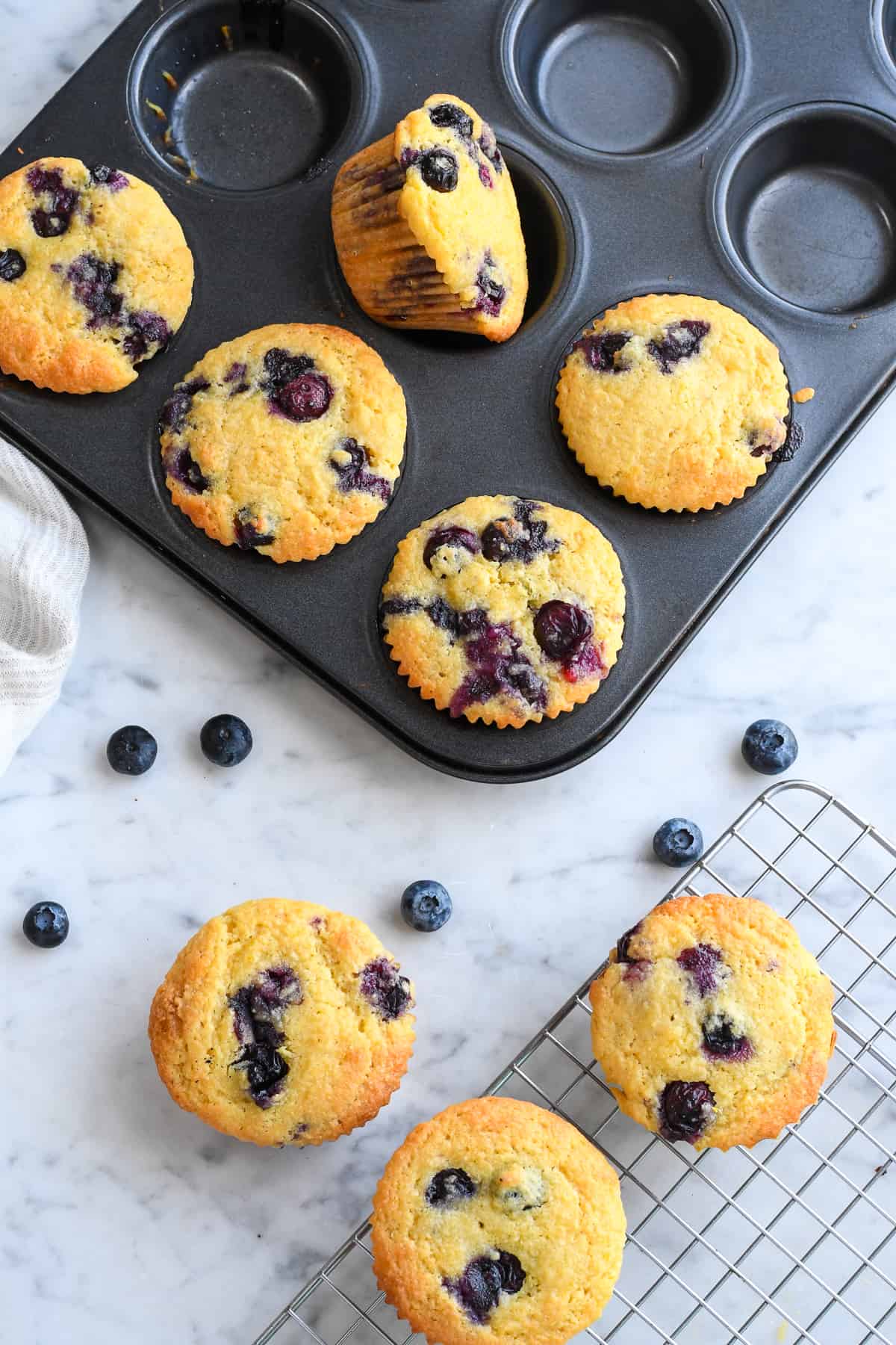 Almond Flour Blueberry Muffins in baking pan with 3 outside of the pan on a rack
