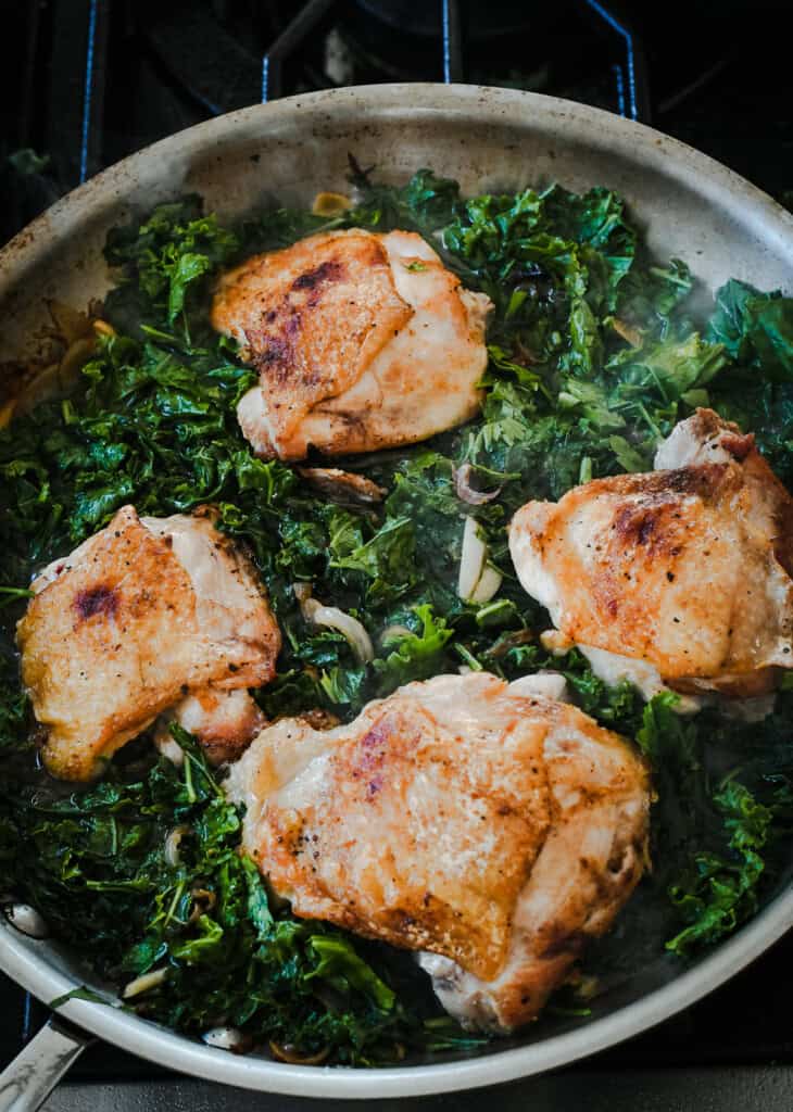 Braised Chicken with Kale, White Beans and Olives chicken and kale in pan