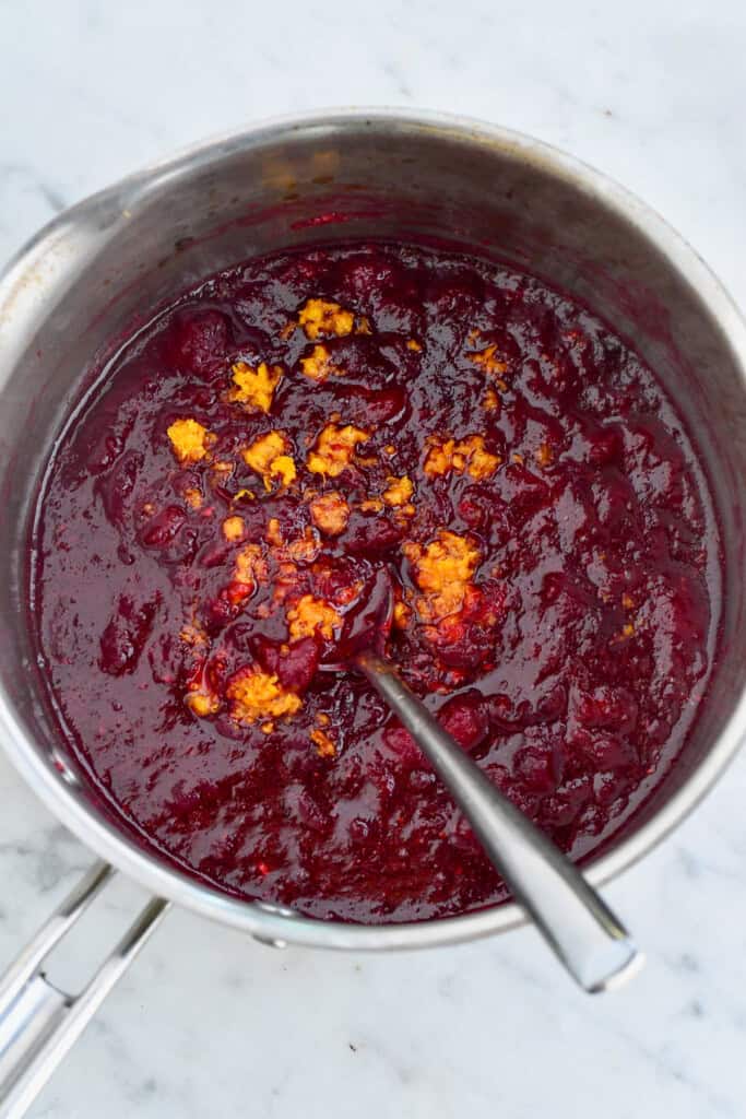 Easy Homemade Cranberry Sauce in pot after cooked with orange zest on top