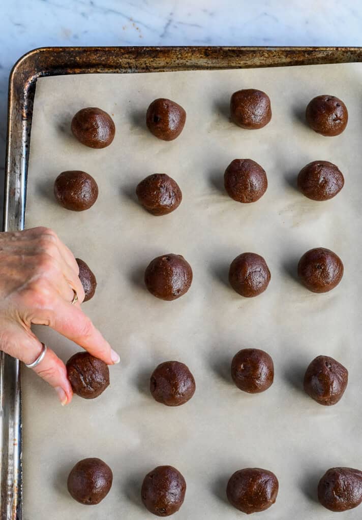 Pumpkin Truffles with Dark Chocolate hand placing rolled truffle on a tray