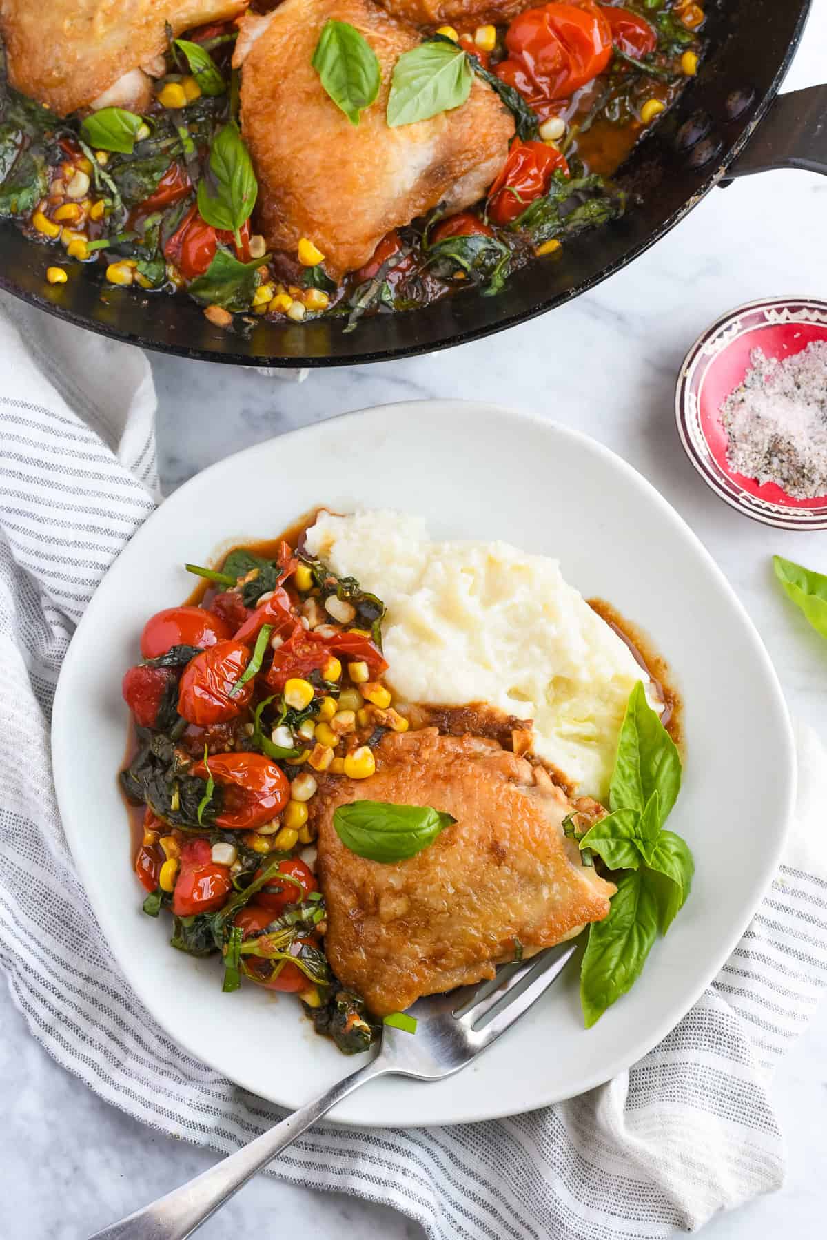 Balsamic Chicken with Tomatoes on plate with cauliflower mash with fork, napkin and pan next to it