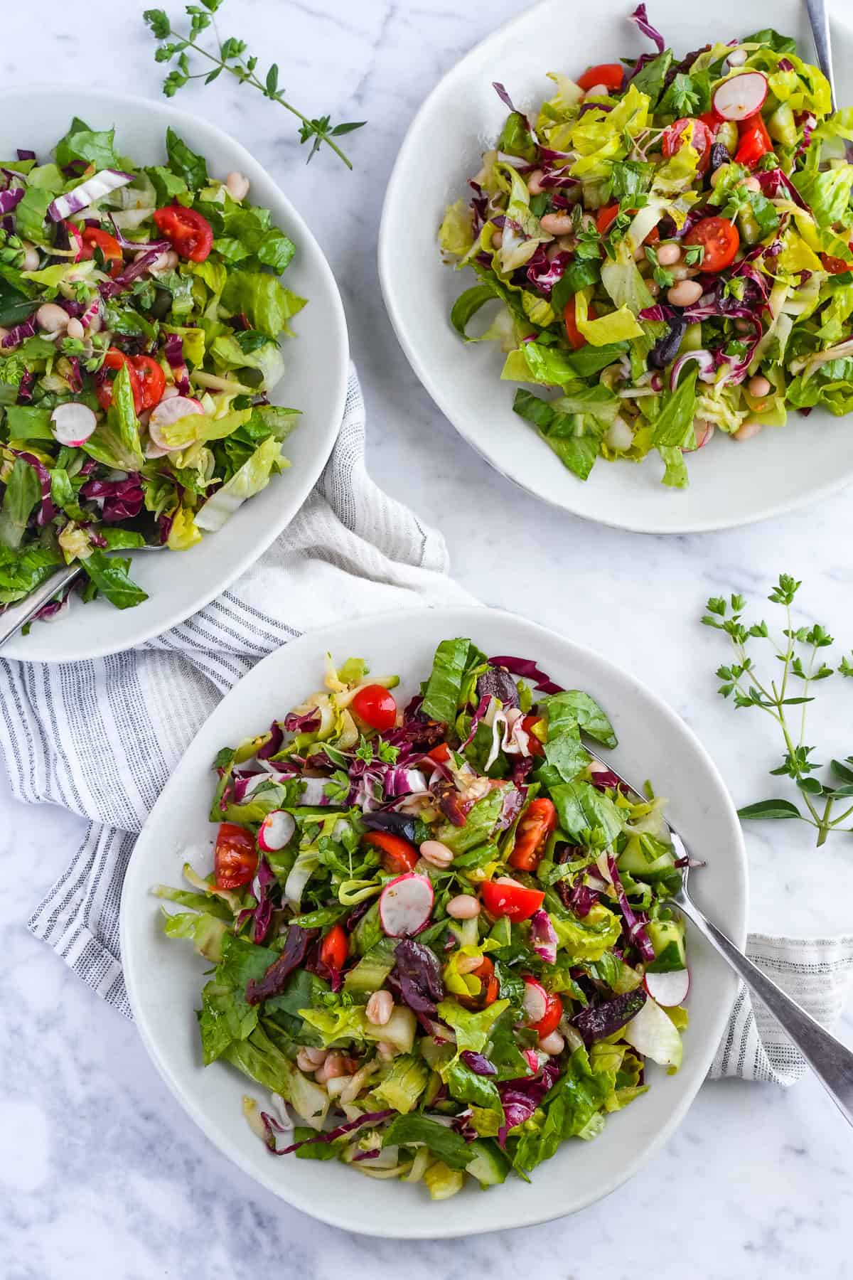 Mediterranean Chopped Salad 3 plates with napkin and fresh oregano