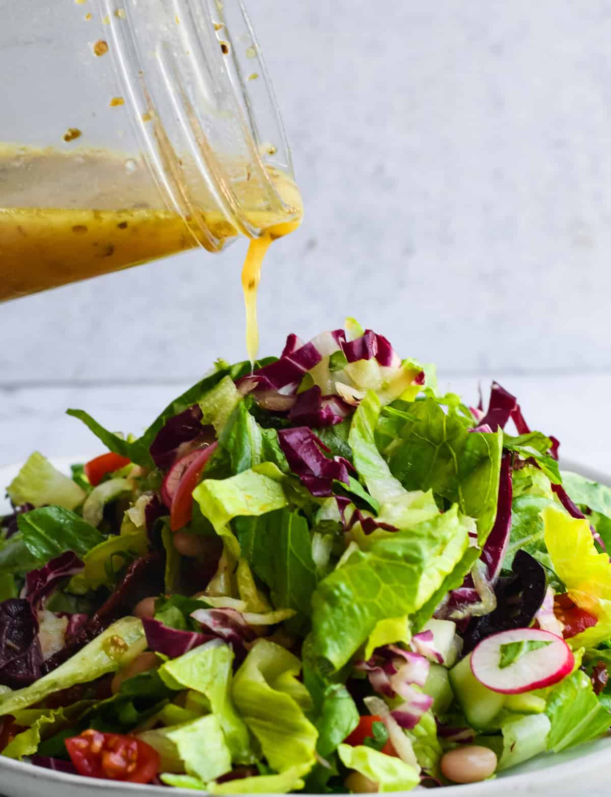 Mediterranean Chopped Salad on plate with dressing being poured