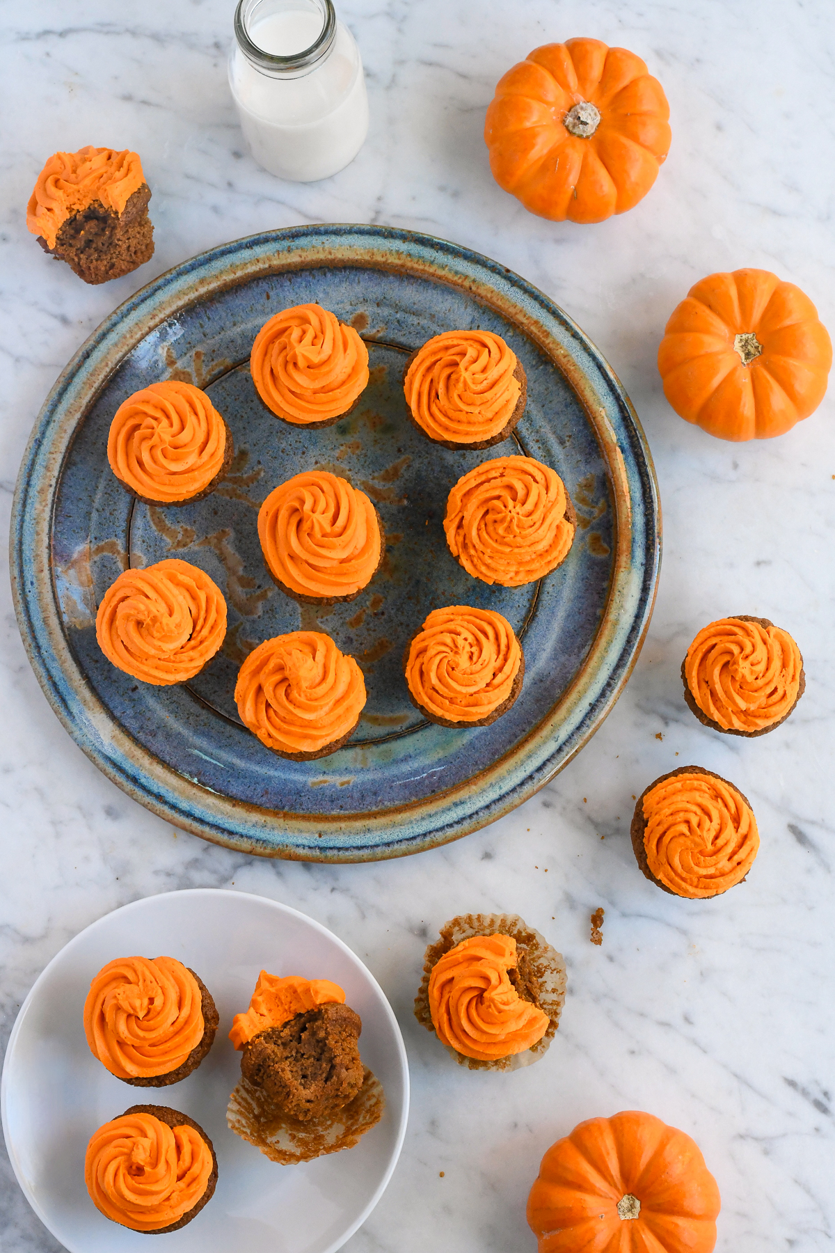 Gluten Free Pumpkin Cupcake on a serving plate with a few cupcakes around and a plate with 3 cupcakes one with a bit out.