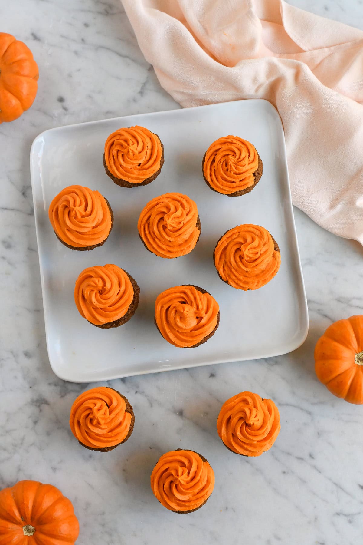 Gluten Free Pumpkin Cupcake on a platter with a few mini pumpkins surrounding