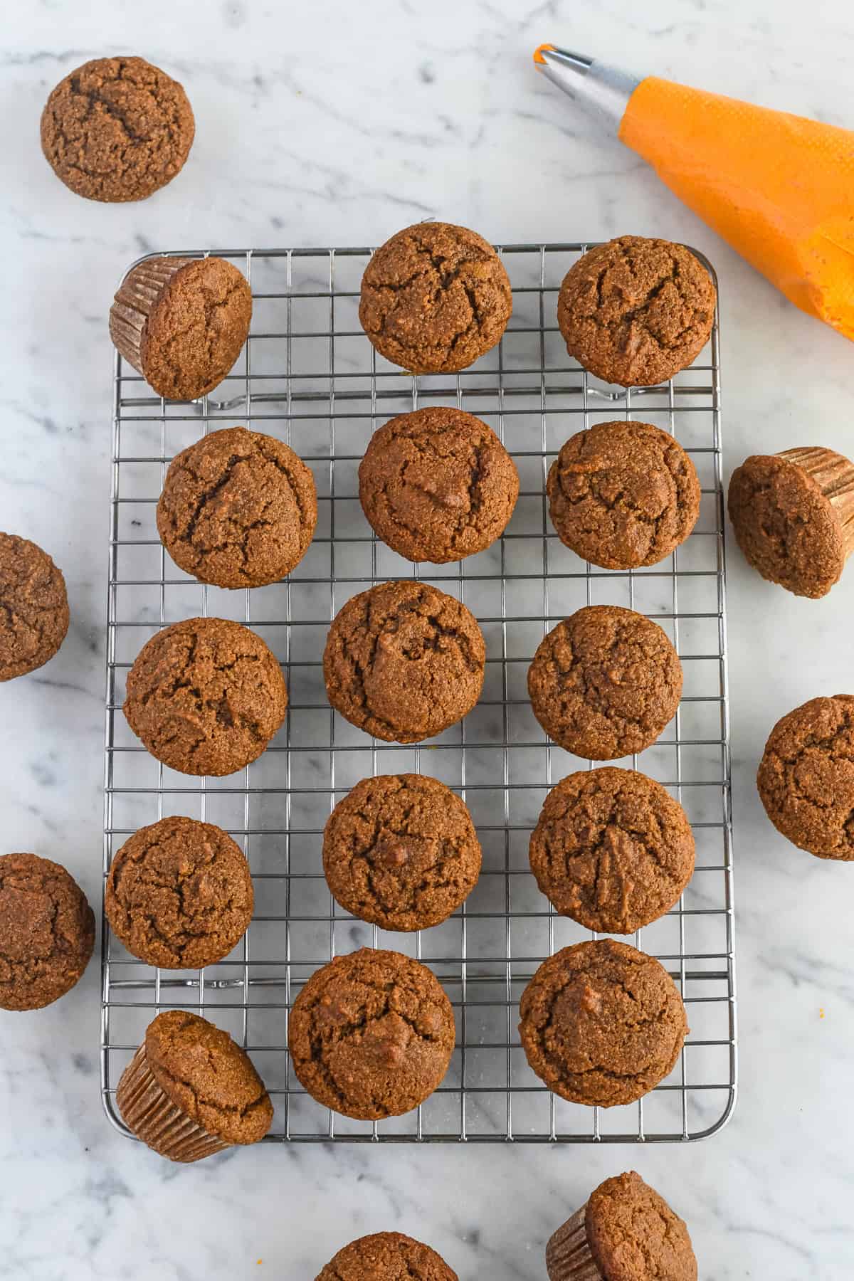 Gluten Free Pumpkin Cupcake on a rack cooling with frosting in pipe bag on the side