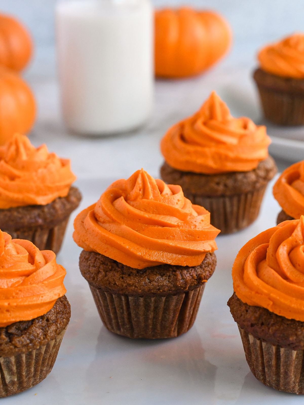 Gluten Free Pumpkin Cupcakes on counter in a line with bottle of milk behind