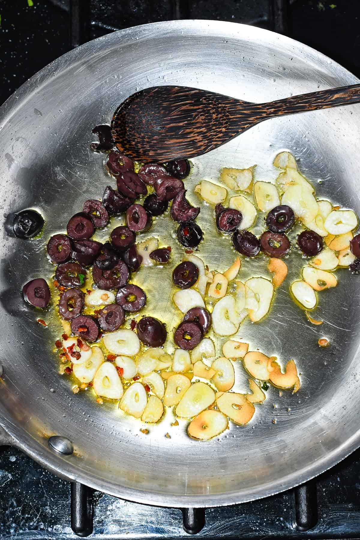 Sautéed Broccoli Rabe with Garlic and Olives sautéing in a pan with garlic olives and red pepper flakes
