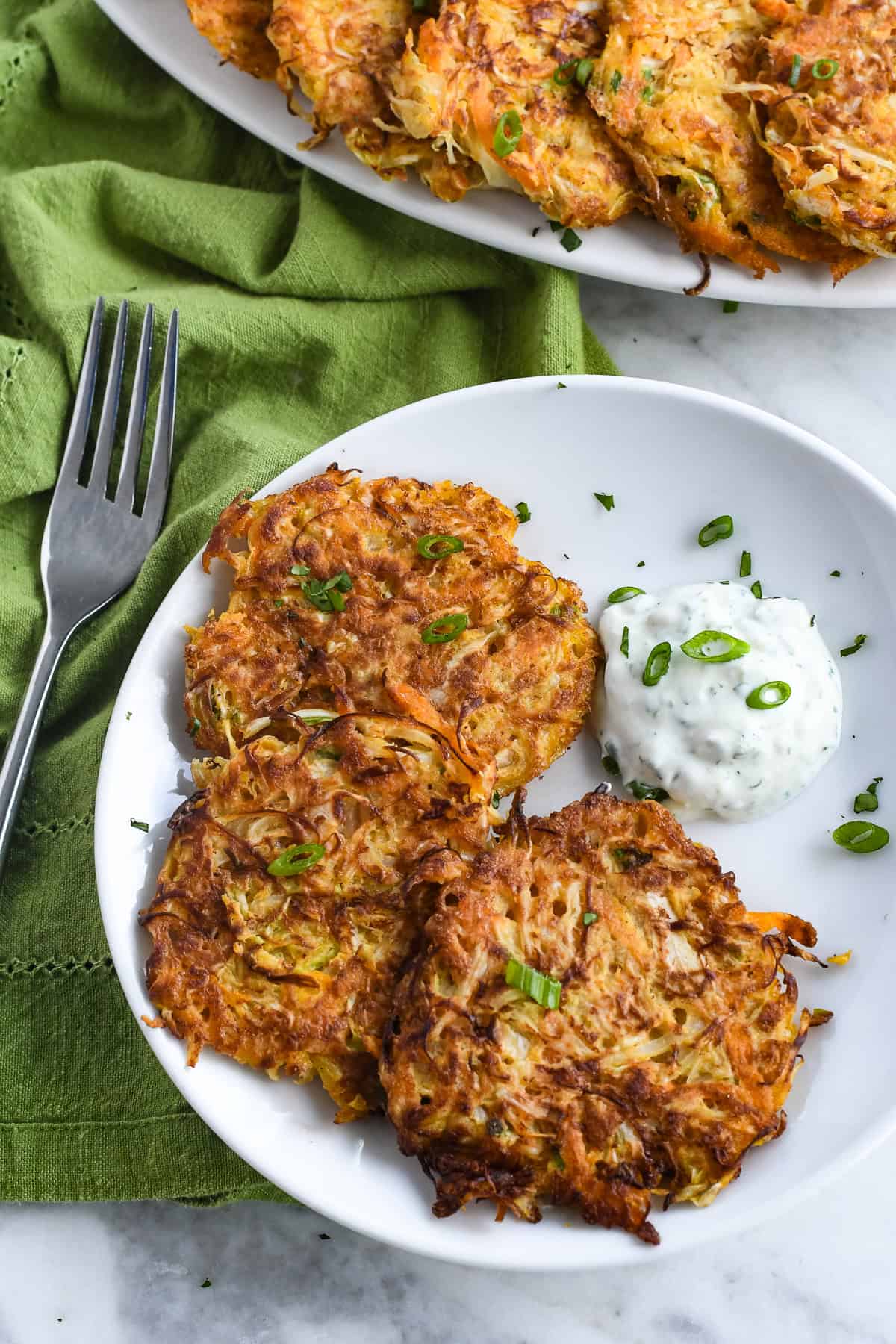 Cabbage Fritters (Gluten Free) 3 fritters on a plate with cilantro lime sauce