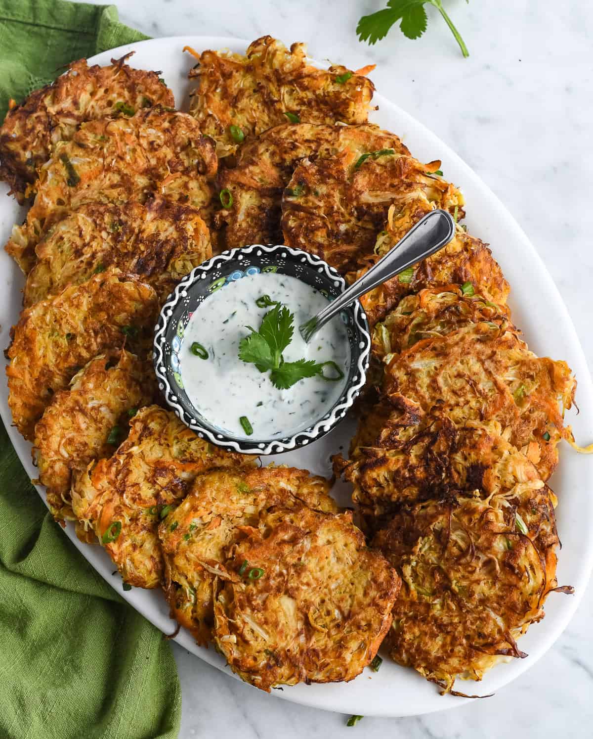 Cabbage Fritters (Gluten Free) on platter with small bowl of cilantro yogurt sauce