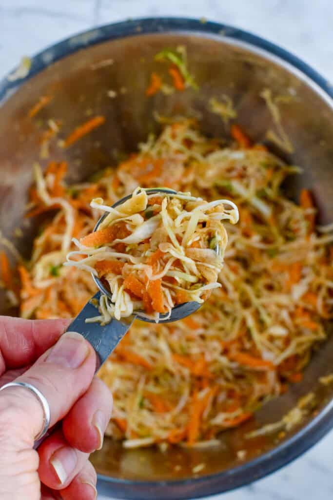 Cabbage Fritters (Gluten Free) hand holding a scoop of fritter mix
