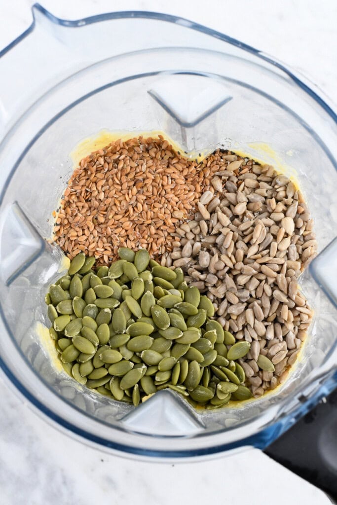 Easy Paleo Seed Bread (Gluten Free) batter with seeds on top in blender