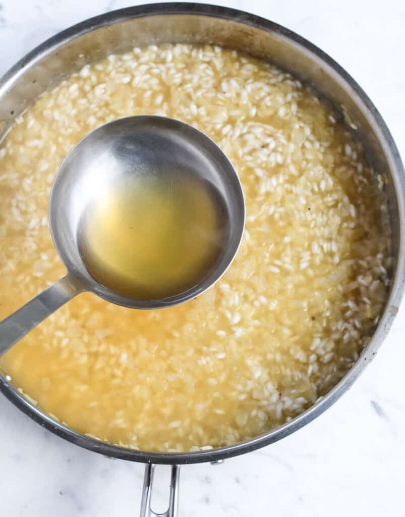 Saffron Risotto with Peas adding additional broth with a ladle