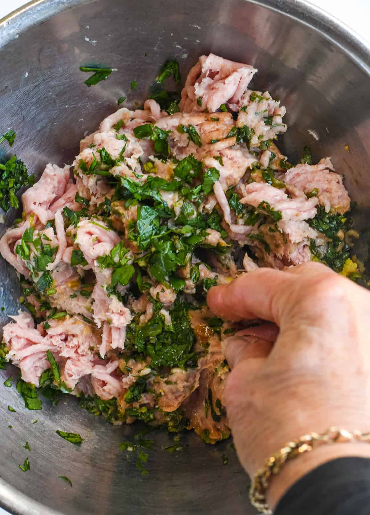 Asian Turkey Meatballs a hand mixing the turkey with the seasonings