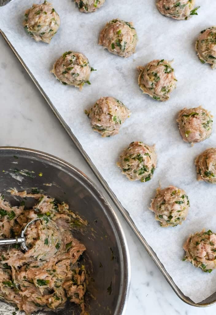 Asian Turkey Meatballs a bowl with scoop of turkey filling and a tray with the raw meatballs