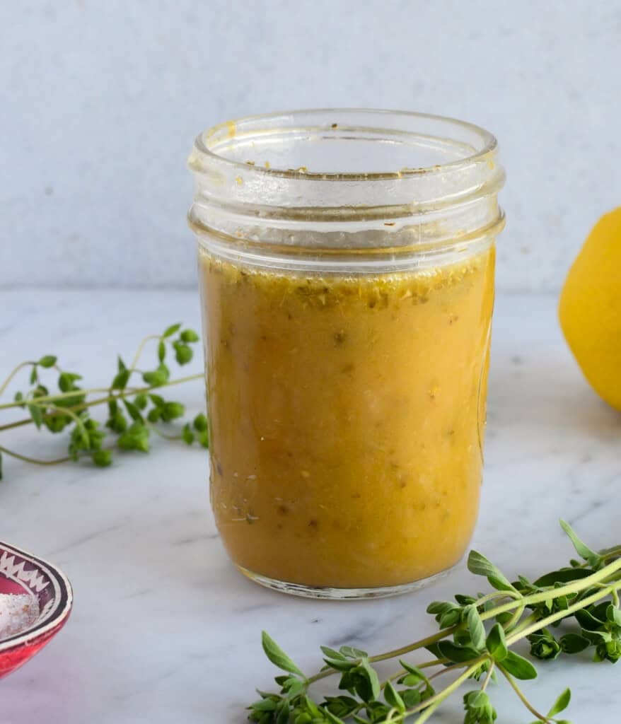 Easy Mediterranean Dressing in jar with fresh oregano on side