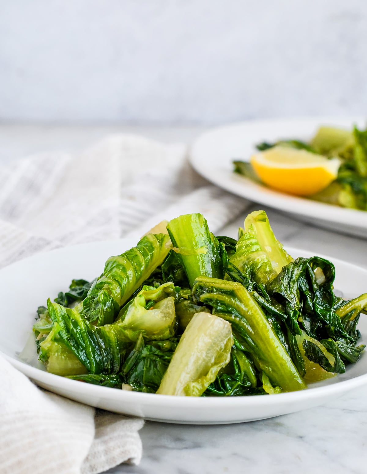 Easy Sautéed Romaine piled on plate with serving try in background