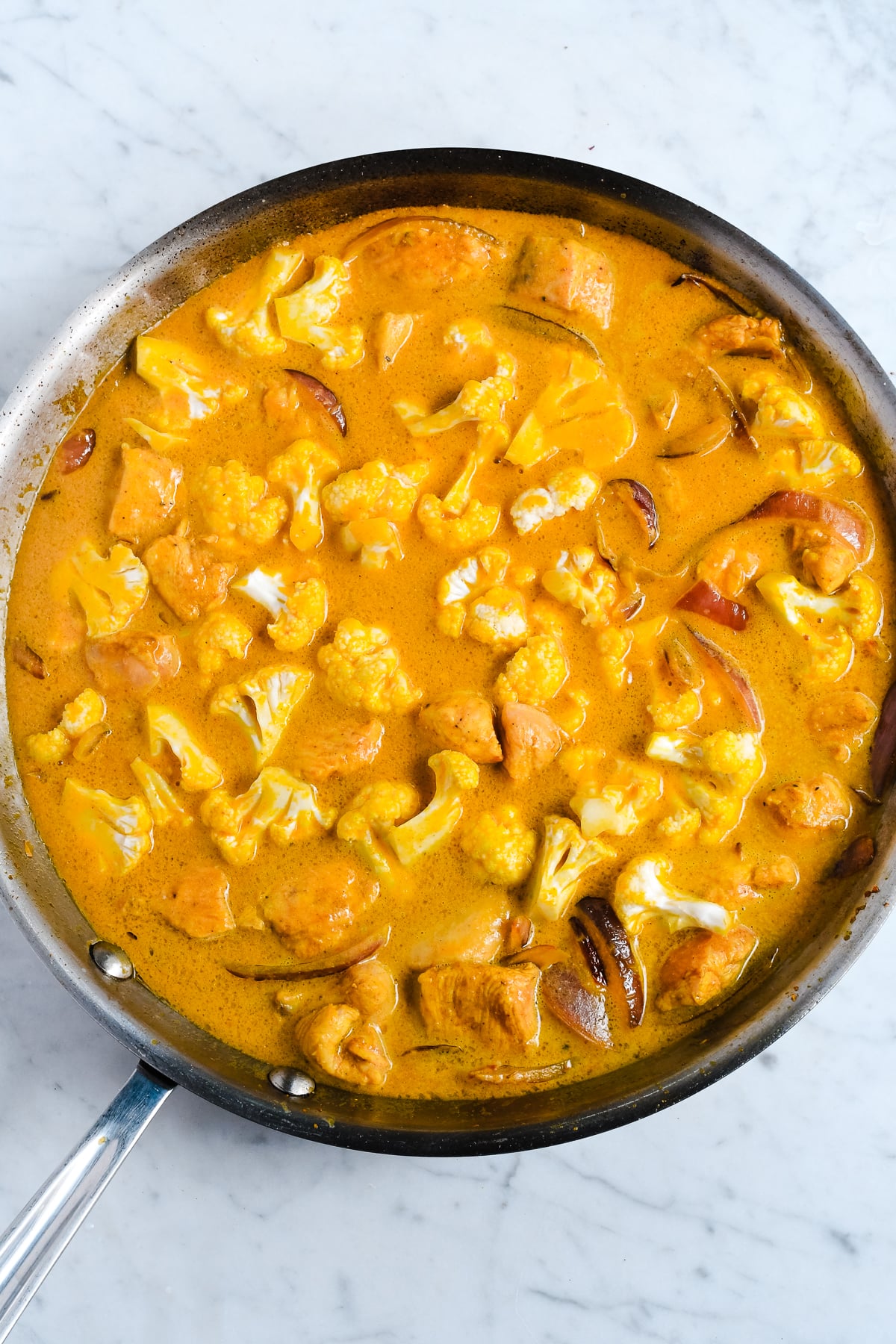 Creamy Pumpkin Curry with Coconut Milk cauliflower mixed into the sauce in pan uncooked